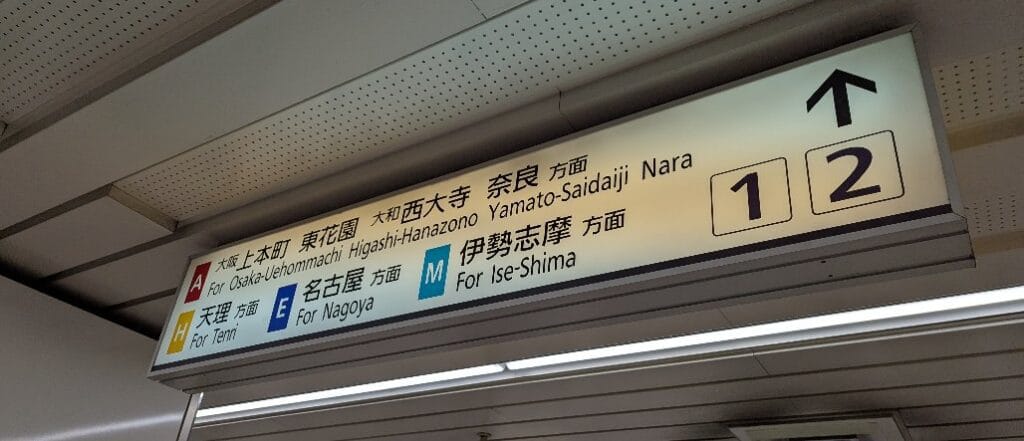 A photo of a train station sign in Japan with Japanese and English text